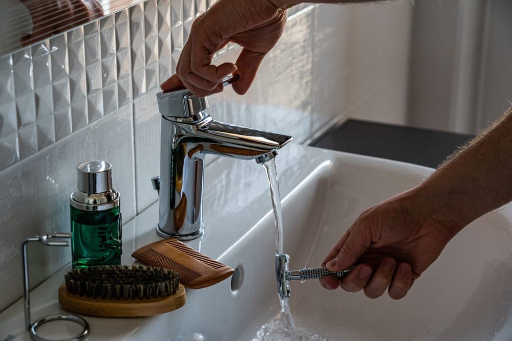 A chrome safety razor resting on a stone surface